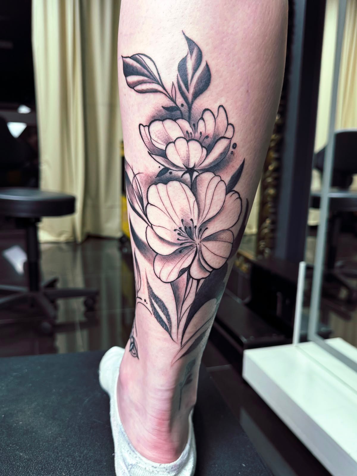 Tatuagem floral em preto e cinza na perna
