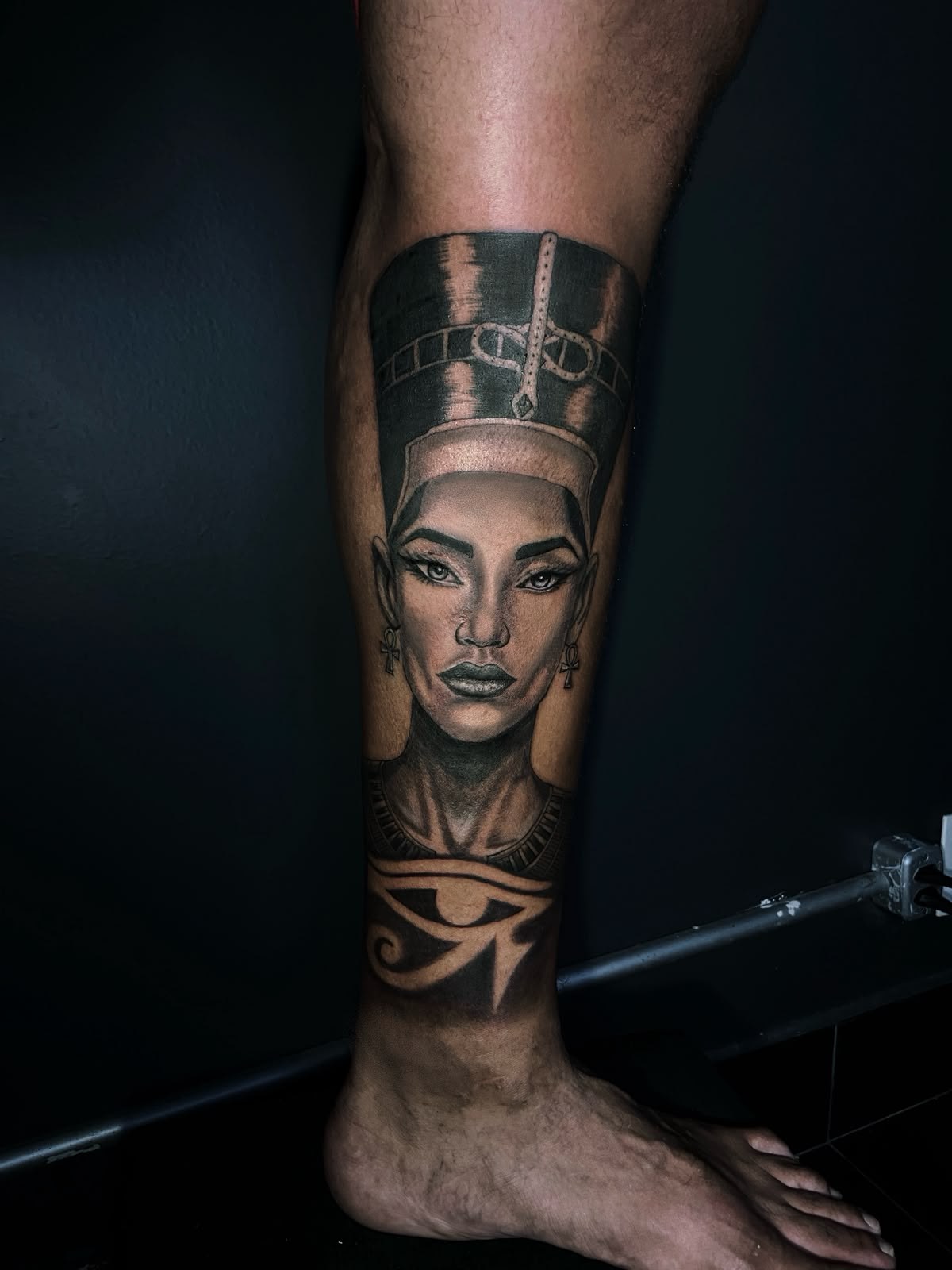 Tatuagem realista de Nefertiti com olho de Hórus na panturrilha